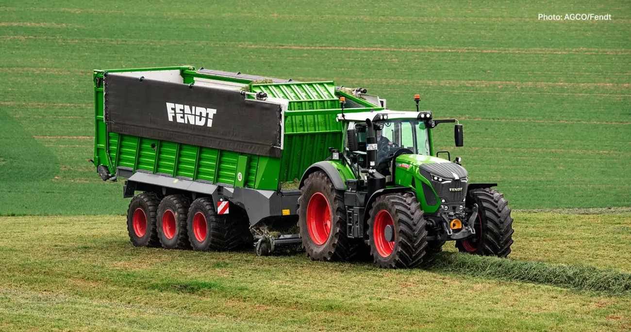 Ein grüner Fendt-Traktor zieht einen großen grünen Anhänger über ein Feld.