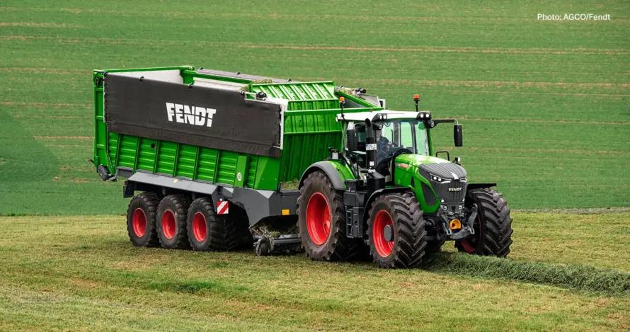 Ein grüner Fendt-Traktor zieht einen großen grünen Anhänger über ein Feld.