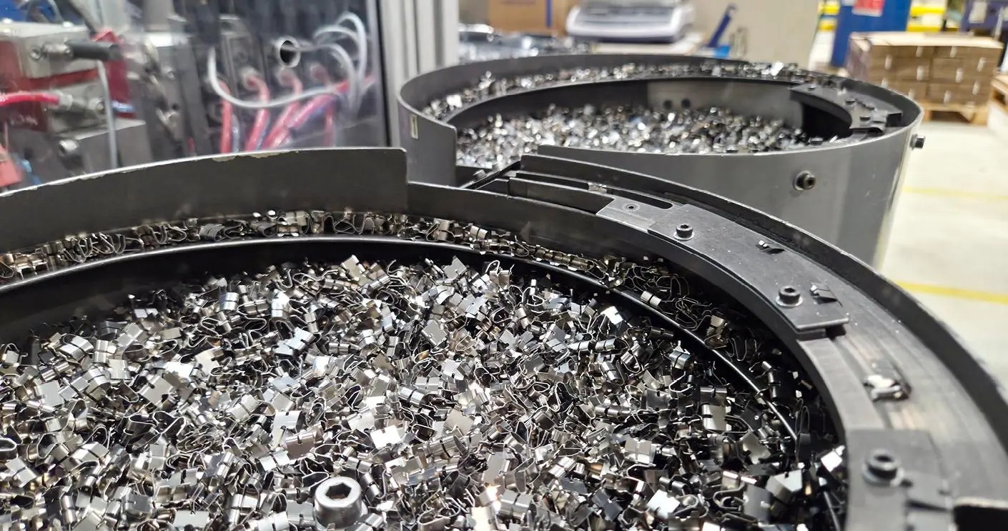 Små metallkomponenter i runda matare på en produktionslinje.