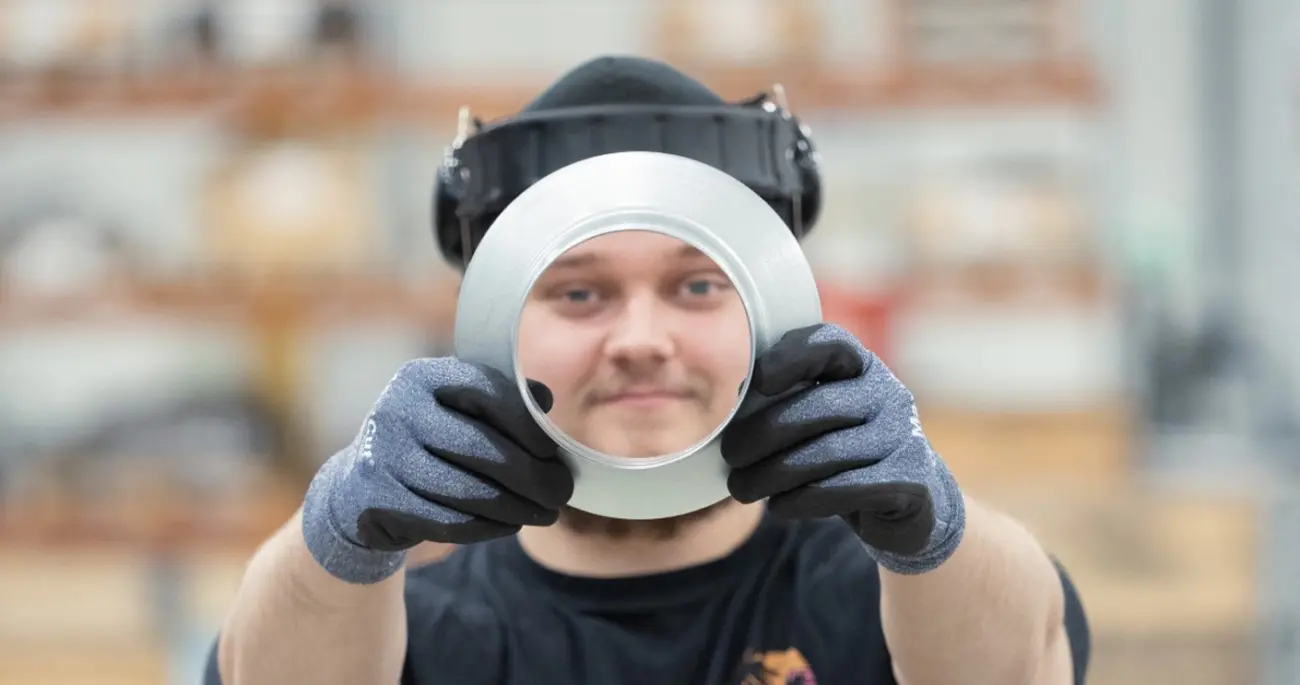A Meconet employee looks through the opening of a ring-shaped metal component.