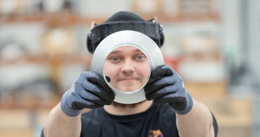 A Meconet employee looks through the opening of a ring-shaped metal component.