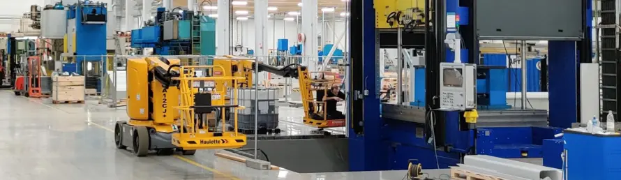 Produktionshalle im Werk Äänekoski mit einer großen Tiefziehpresse und einer Hubarbeitsbühne.